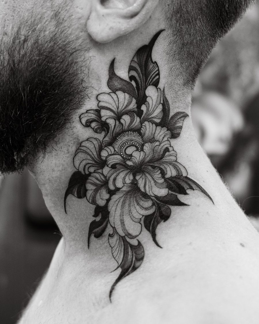 A dark ornamental peony tattooed on the side of a neck