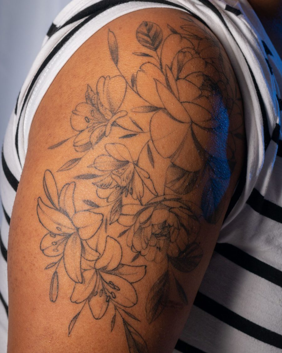 A fine-line peony and lily half-sleeve on a shoulder, healed