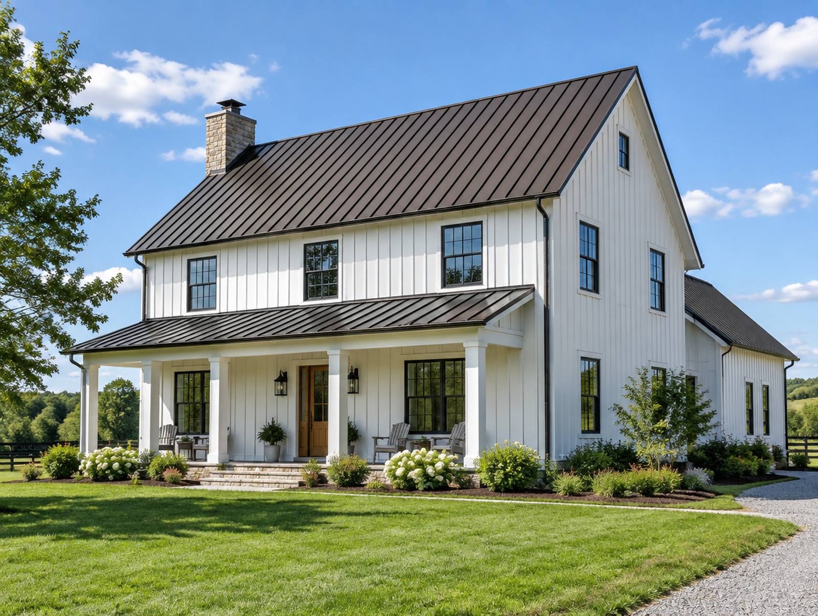 A white farmhouse with a new dark bronze standing-seam metal roof on a sunny day.